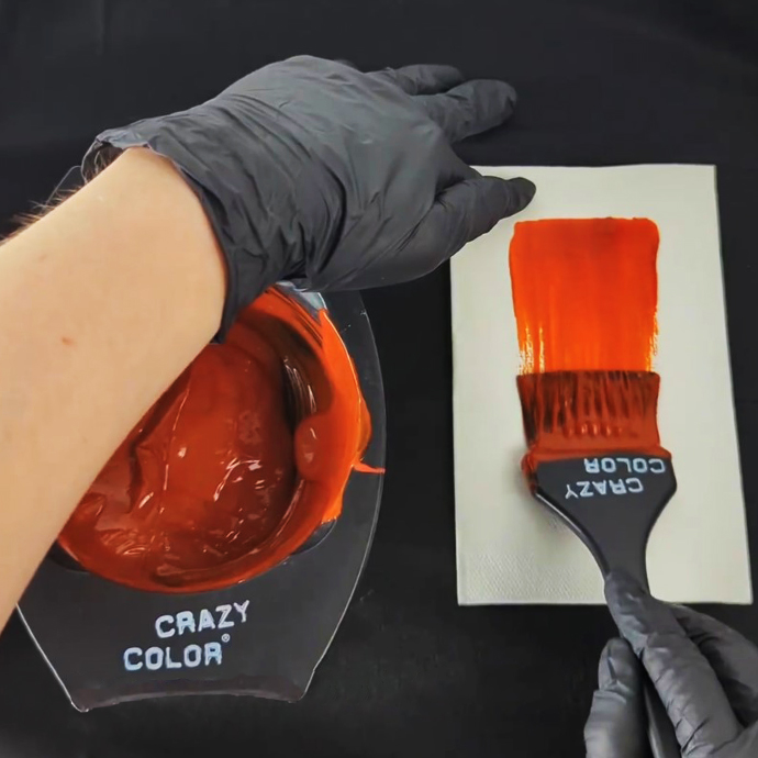 image of woman using crazy color bowl and brush to mix bright orange hair dye